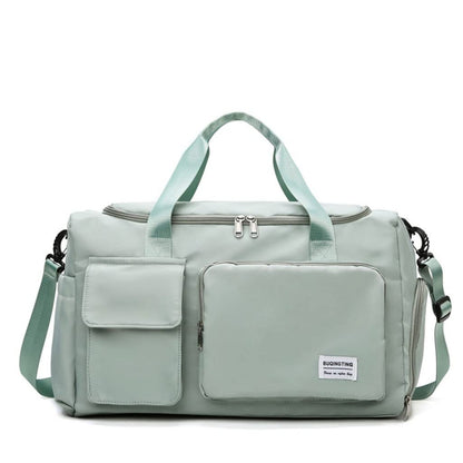 Bolso de viaje verde claro con múltiples bolsillos y correa ajustable.