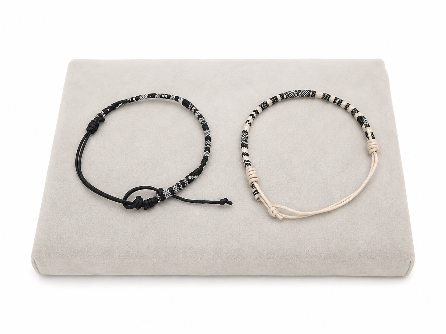 Set de 2 pulseras ajustables en negro y beige con diseño tejido estampado.