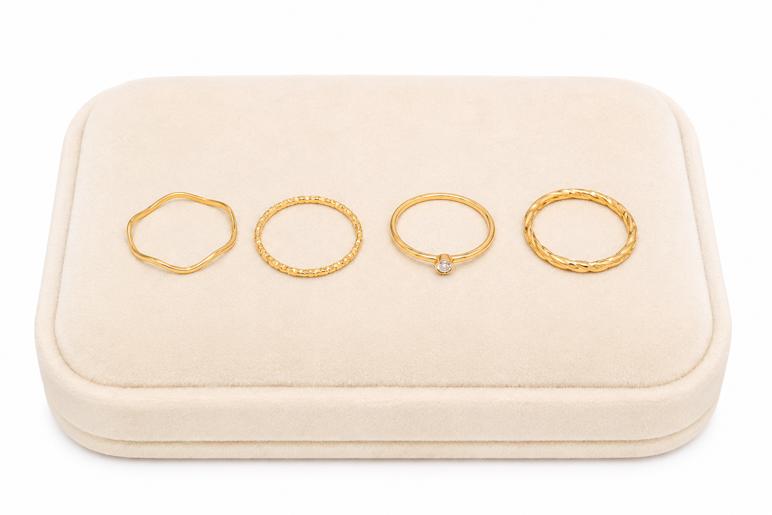 Set de 4 anillos dorados con diseños ondulados, texturizados, trenzados y piedra decorativa.