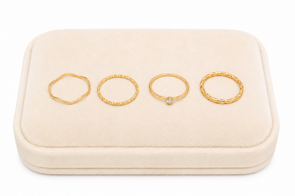 Set de 4 anillos dorados con diseños ondulados, texturizados, trenzados y piedra decorativa.