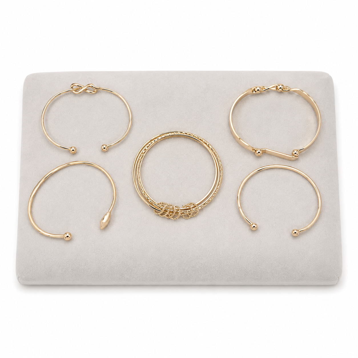 Set de 5 brazaletes dorados con diseños abiertos y ornamentales.