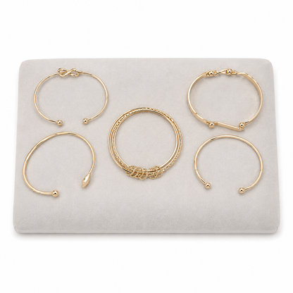 Set de 5 brazaletes dorados con diseños abiertos y ornamentales.