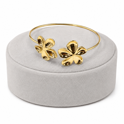 Pulsera dorada abierta con diseño de flores.