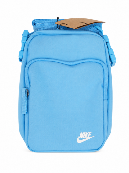 Bolso cruzado color azul claro con bolsillo frontal y correa ajustable.