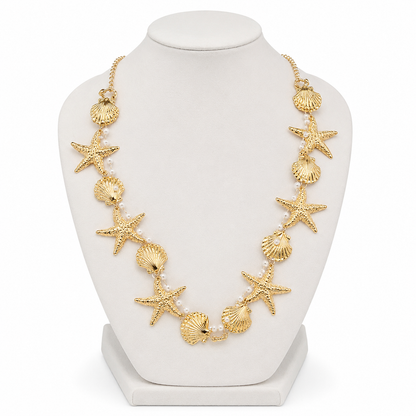 Collar dorado con diseño de estrellas de mar, conchas y perlas blancas.
