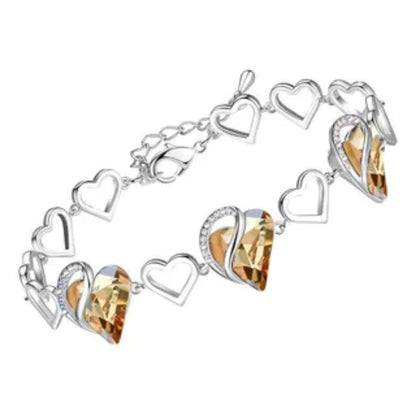 Pulsera plateada con dijes de corazones y cristales color ámbar.