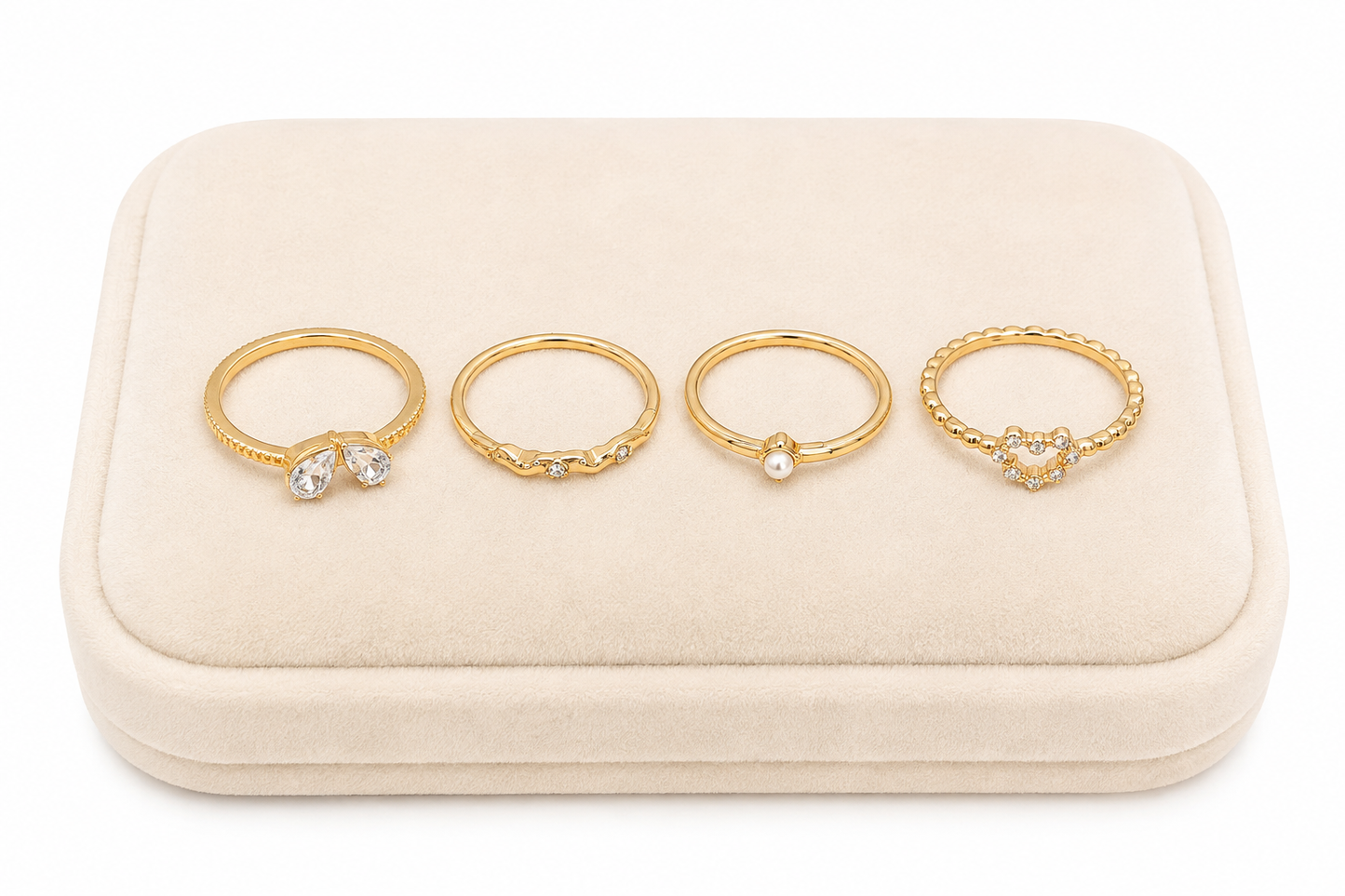 Set de 4 anillos dorados con detalles brillantes, corazón y perla.