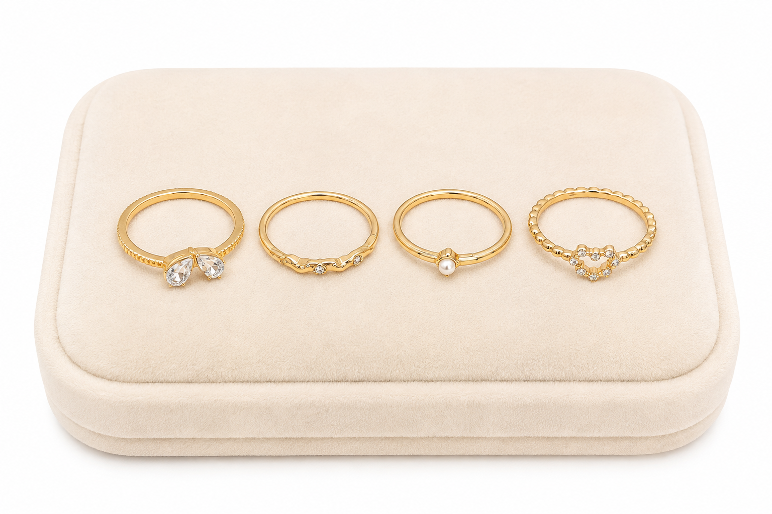 Set de 4 anillos dorados con detalles brillantes, corazón y perla.