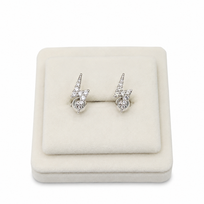Aretes plateados con diseño de rayo y piedras brillantes.