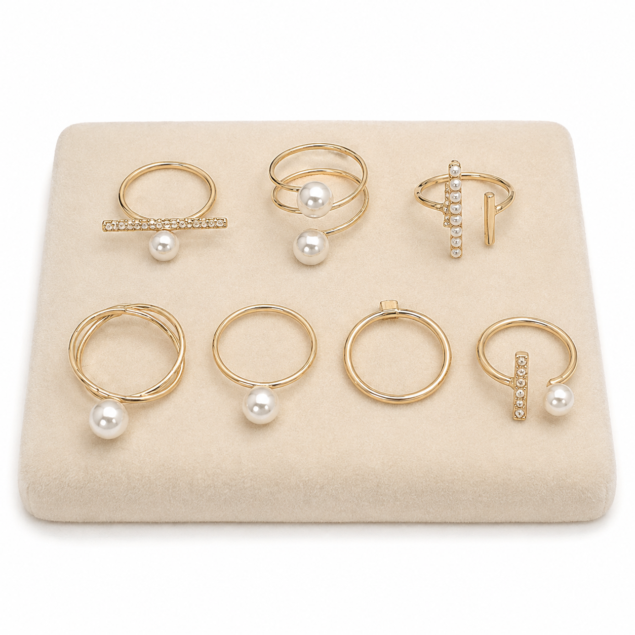 Set de 7 anillos dorados con diseños variados y detalles perlados.