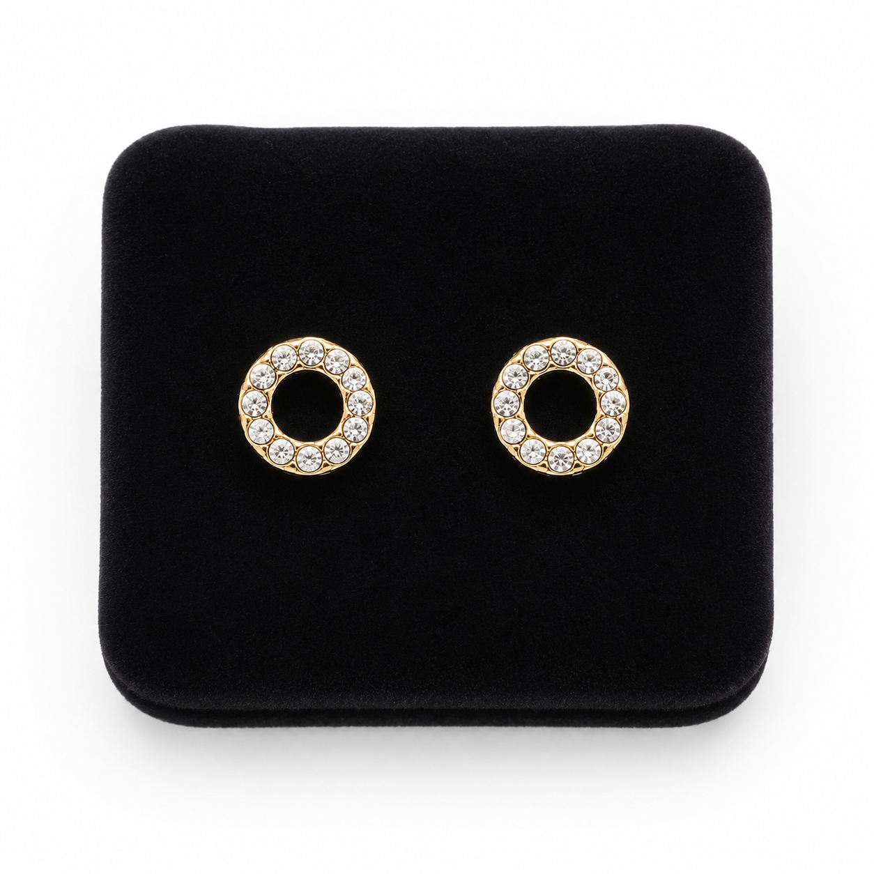 Aretes de botón circulares dorados con aro de piedras transparentes.