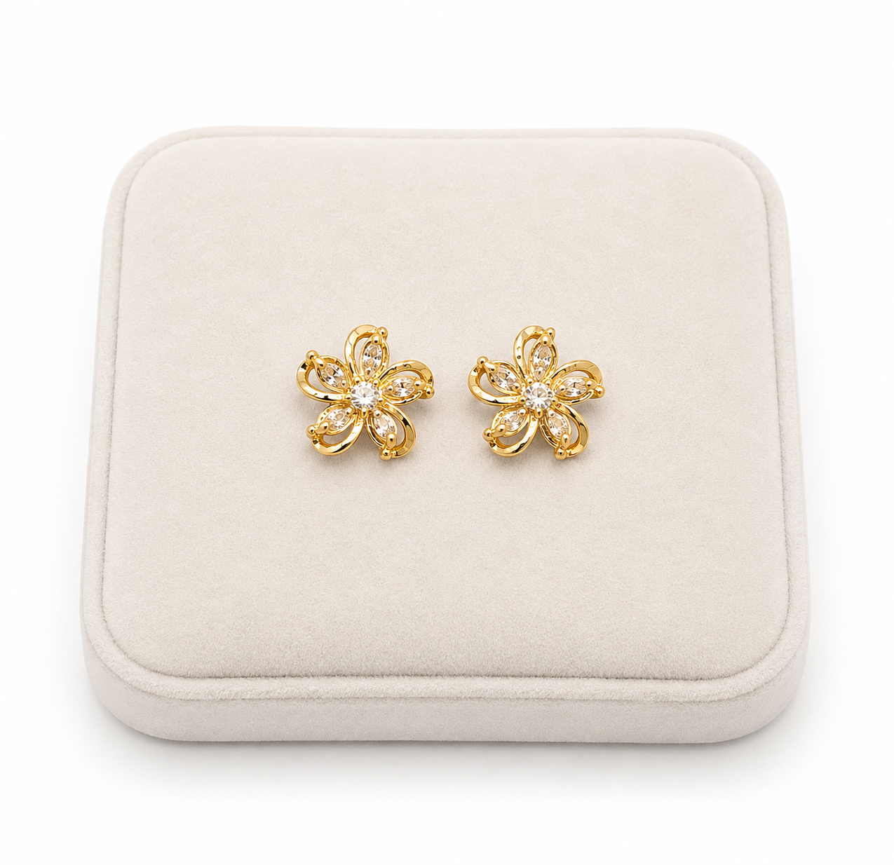 Aretes de flores doradas con detalles brillantes transparentes.
