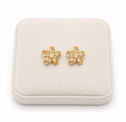 Aretes de flores doradas con detalles brillantes transparentes.