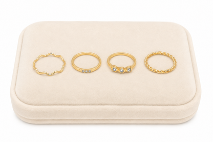 Set de 4 anillos dorados con diseños ondulados, trenzados y detalles brillantes.