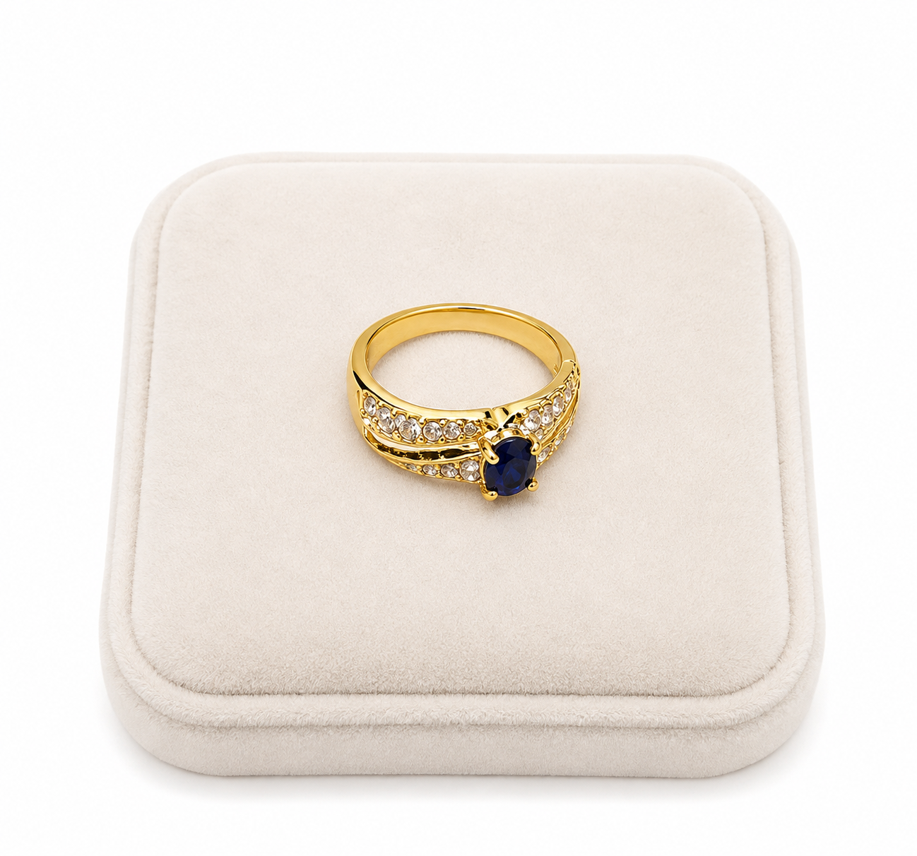 Anillo dorado con piedra central azul y detalles brillantes.