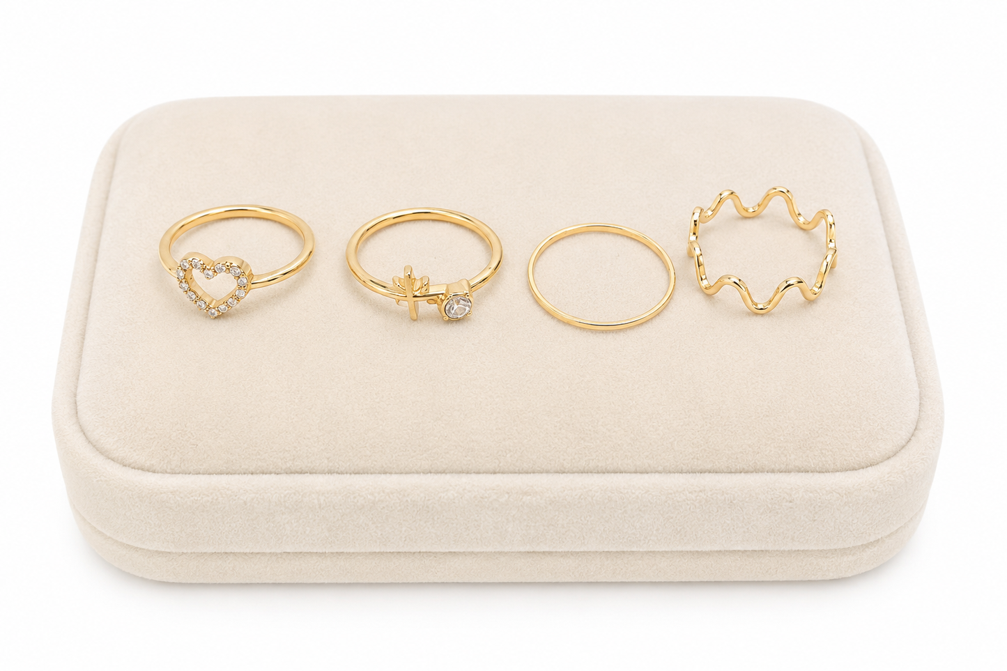 Set de 4 anillos dorados con diseños de corazón, cruz, aro liso y ondas.