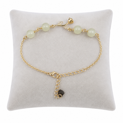 Pulsera de cadena dorada con cuentas verde claro y detalles florales.