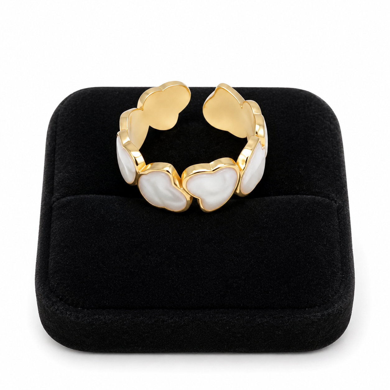 Anillo abierto dorado con diseño de corazones en tonos blanco y beige.