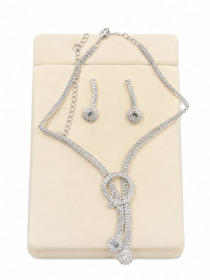 Conjunto de collar, pulsera y pendientes con diseño brillante color plateado.