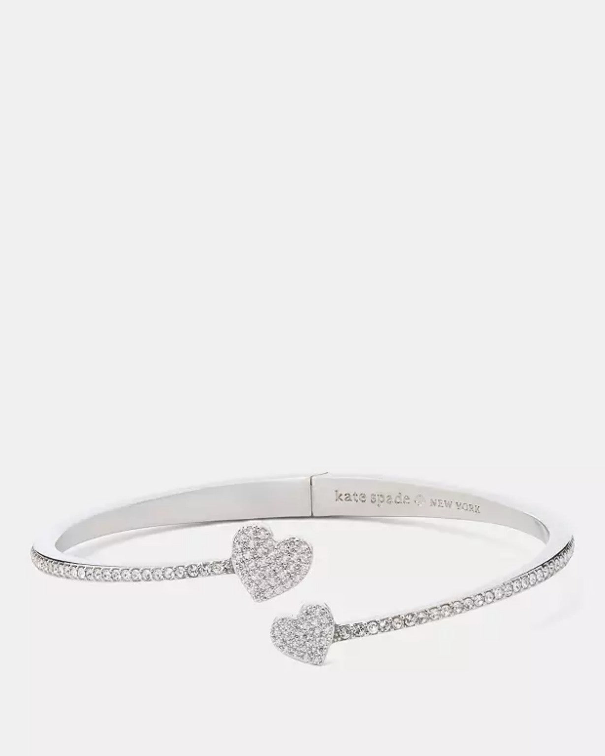 Brazalete plateado abierto con corazones y cristales decorativos.
