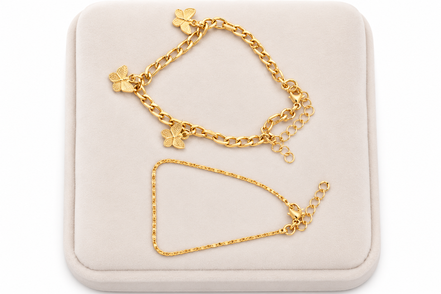 Set de 2 pulseras doradas con dijes de mariposa y diseño de cadena fina.