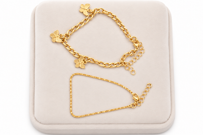Set de 2 pulseras doradas con dijes de mariposa y diseño de cadena fina.
