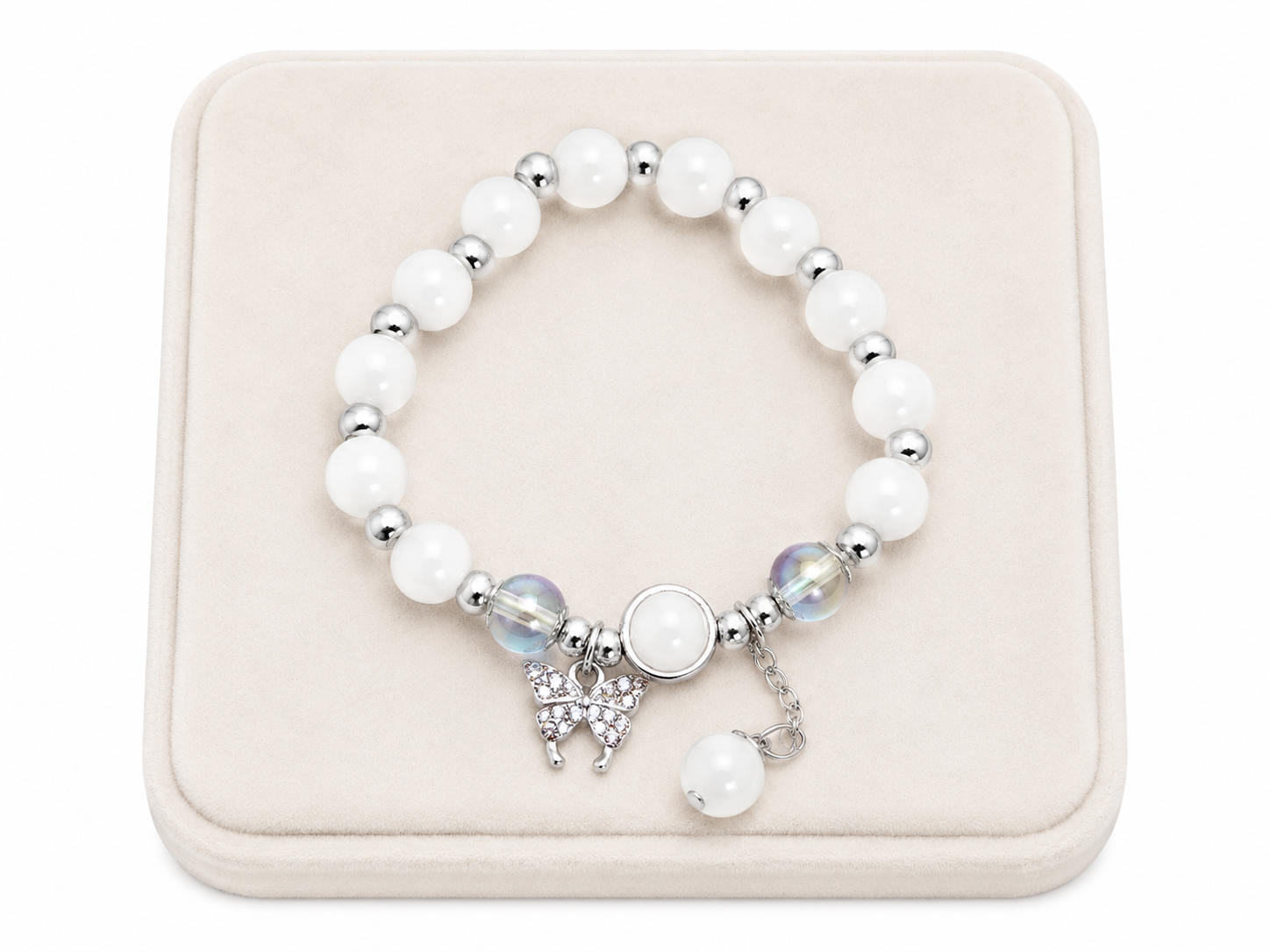Pulsera elástica con cuentas blancas, dijes de mariposa y detalles en color plateado.