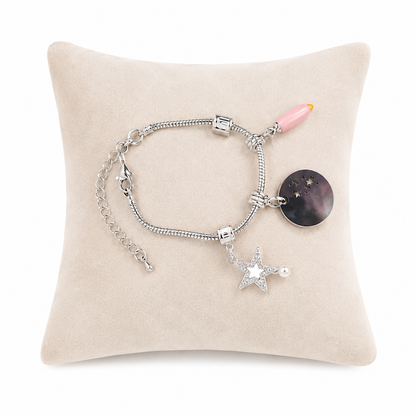 Pulsera con dijes de estrella, disco y detalle rosa en color plateado.