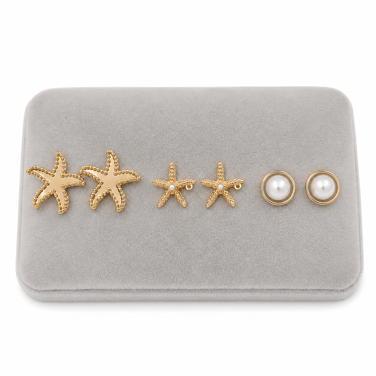Set de tres pares de aretes dorados con estrellas de mar y perlas blancas.