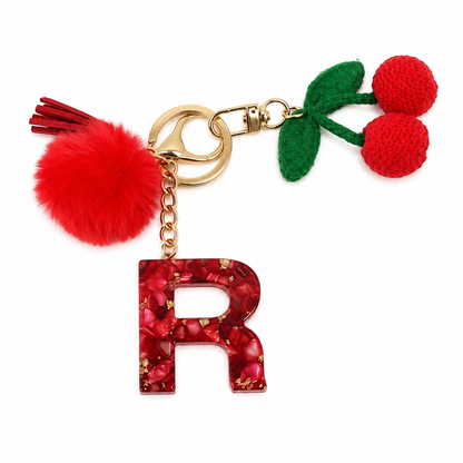 Llavero rojo con inicial R, cerezas y pompón.