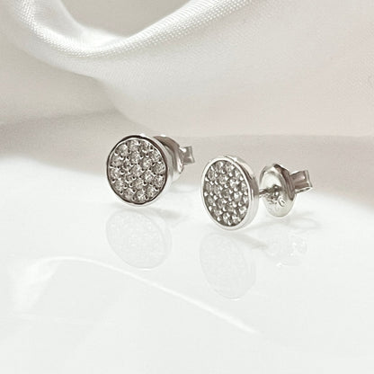 Aretes redondos plateados con diseño de piedras brillantes.