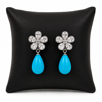 Aretes colgantes plateados con piedras turquesa en forma de gota.